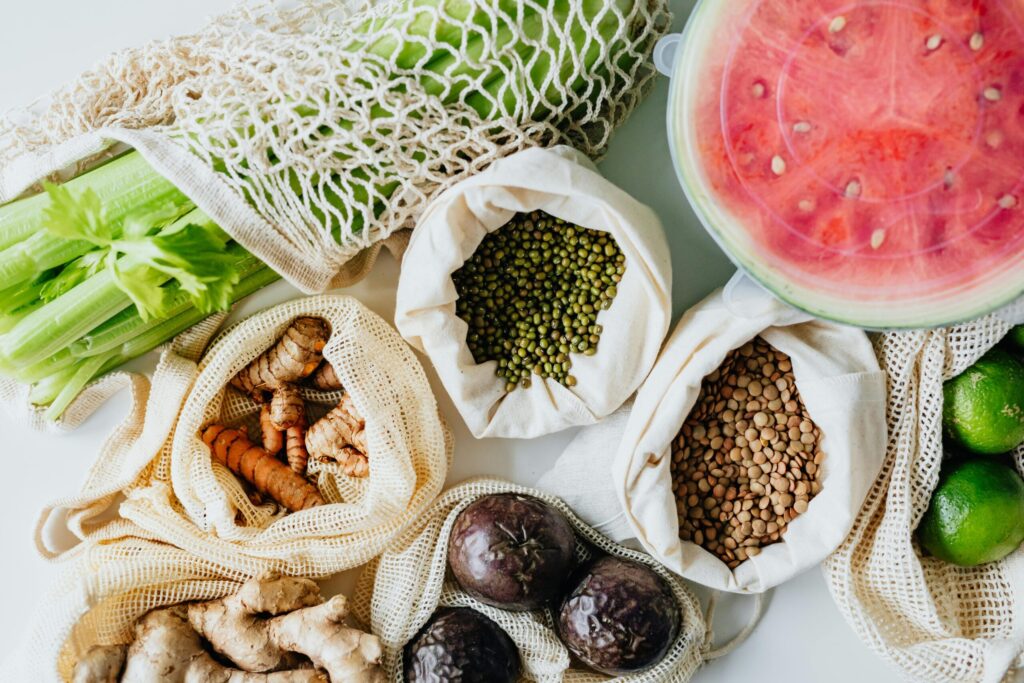 Top view of fresh produce, spices, and grains in reusable bags, highlighting eco-friendly living.